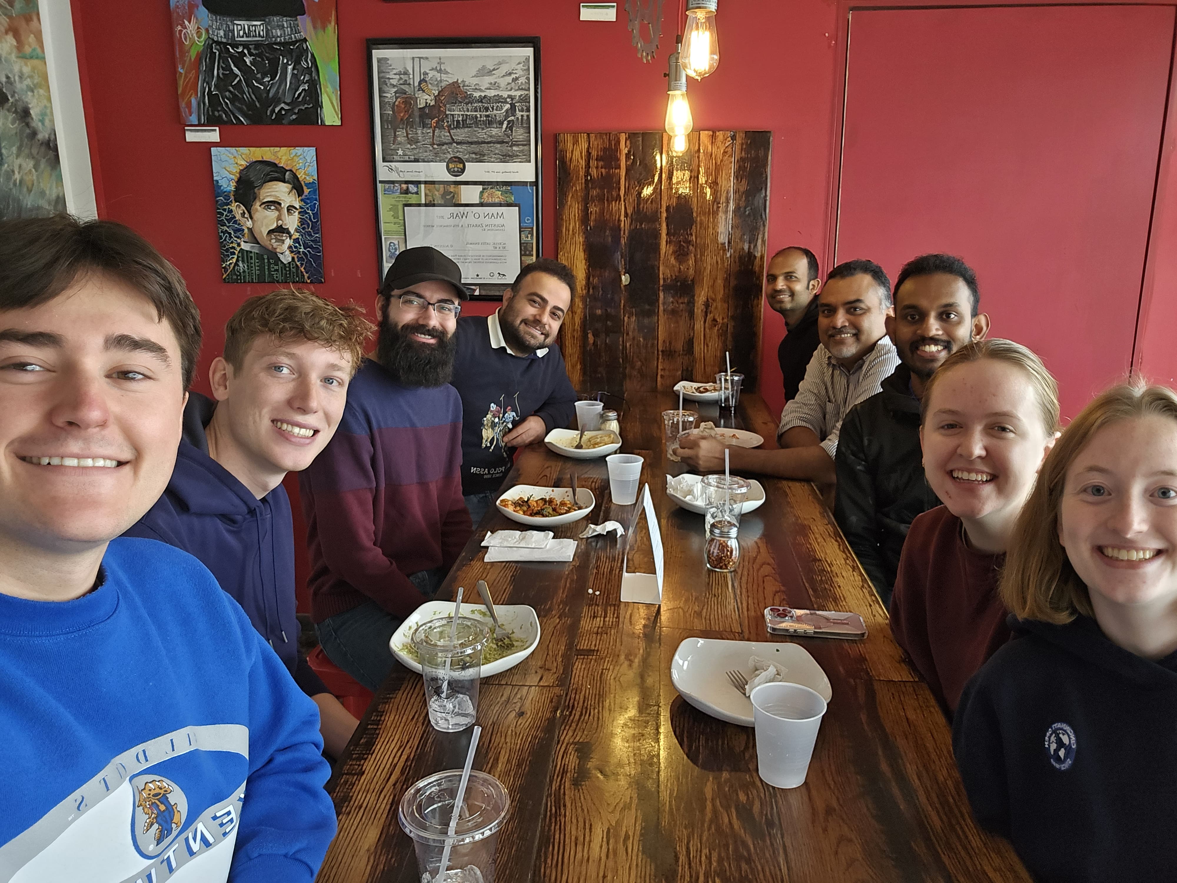 Photo of Dr. Abheetha Peiris with seven students and a visitng professor at a restaurant seated around a table